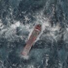 Supply chain resilience: aerial view of a container ship navigating rough, foamy seas during a global disruption.